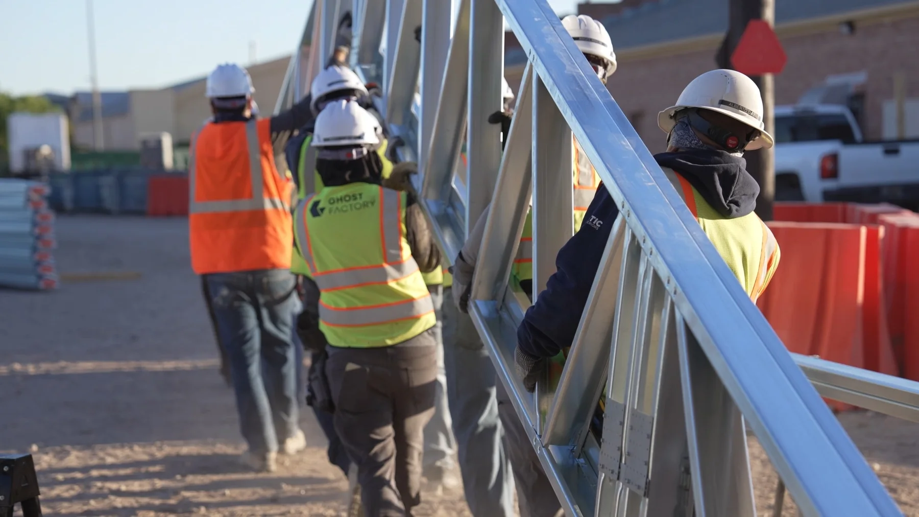 Ghost Factory crew carrying a steel truss on a construction site